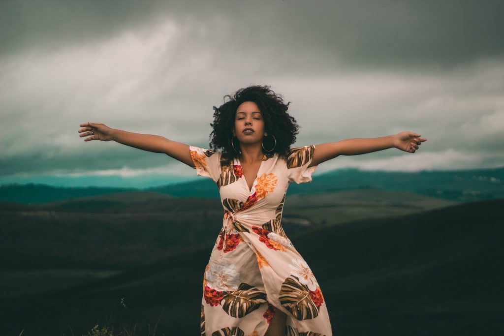 woman in white and red floral dress standing on green grass 3605015